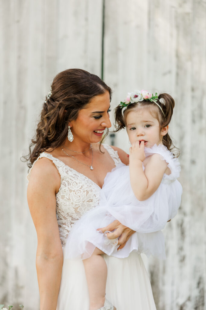 A bride holds her flower girl at Northfork Farms, Oswego, IL

Photos by Amanda Banik Photography.