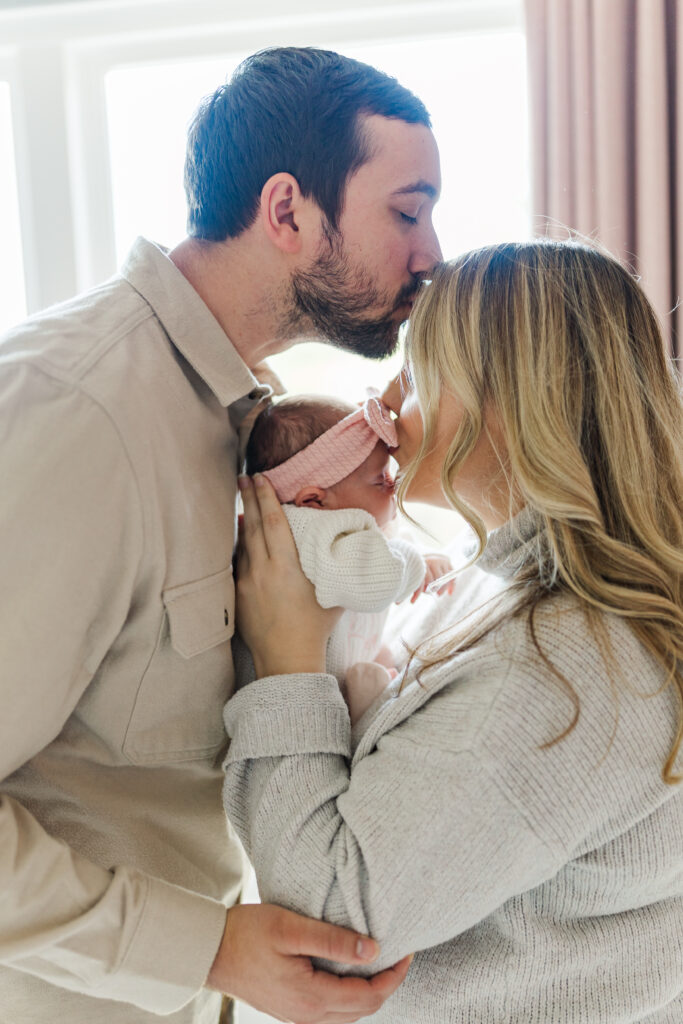 A mom and dad share kisses with their newborn baby.
Central Illinois Newborn Photographer.
Amanda Banik Photography