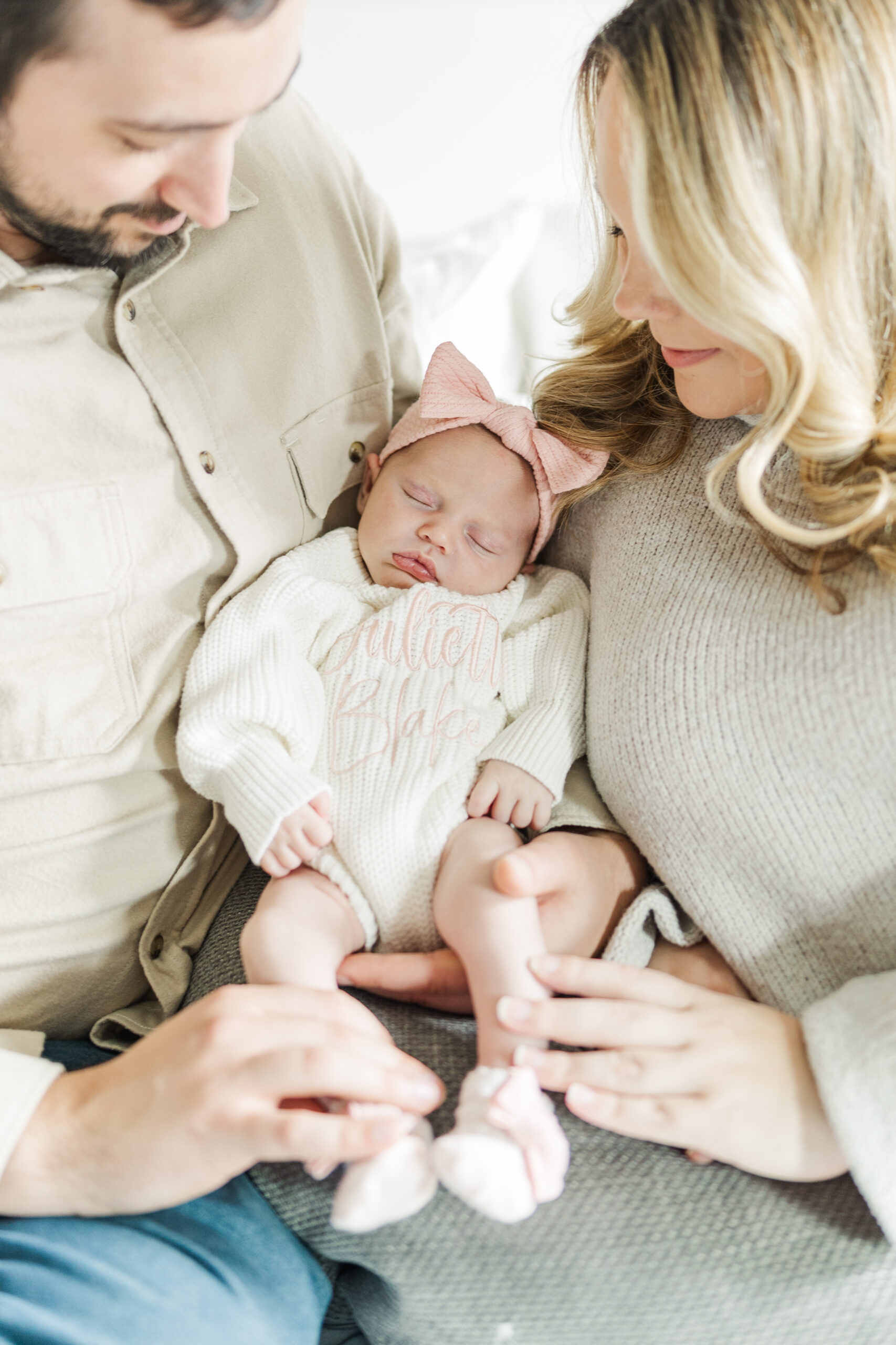 A newborn baby girl sleeps in her parents' arms. Central Illinois Newborn Photographer. Amanda Banik Photography