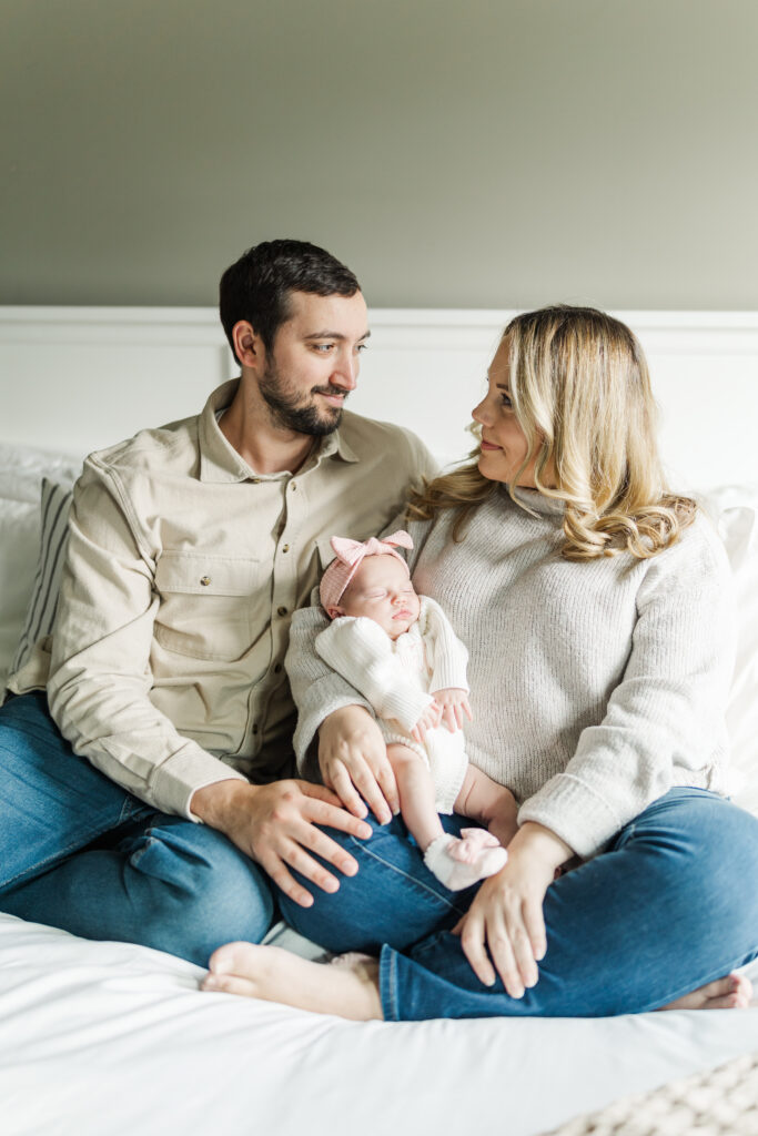 A mom and dad proudly smile at each other holding their newborn baby. Central Illinois Newborn Photographer. Amanda Banik Photography
